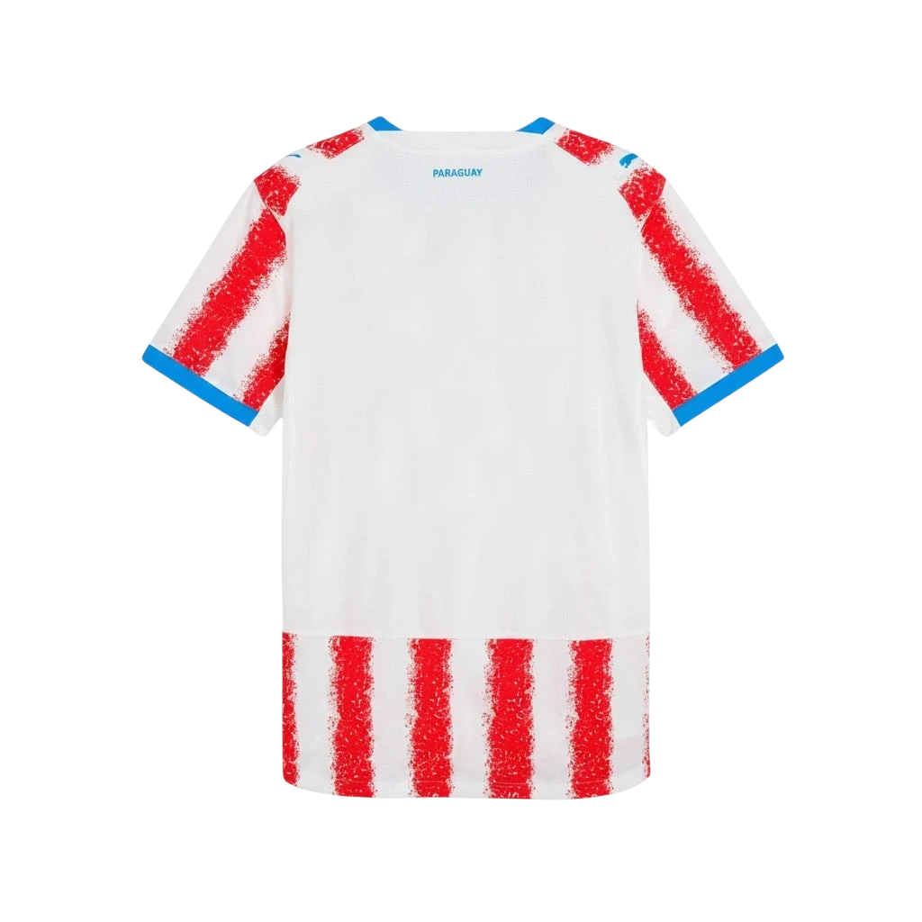 Camiseta de fútbol blanca de Paraguay de primera equipación con detalles de rayas rojas y ribetes azules en cuello y mangas.